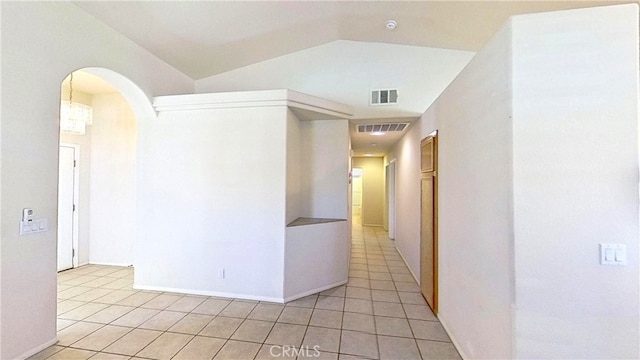 hall featuring lofted ceiling, light tile patterned floors, arched walkways, and visible vents