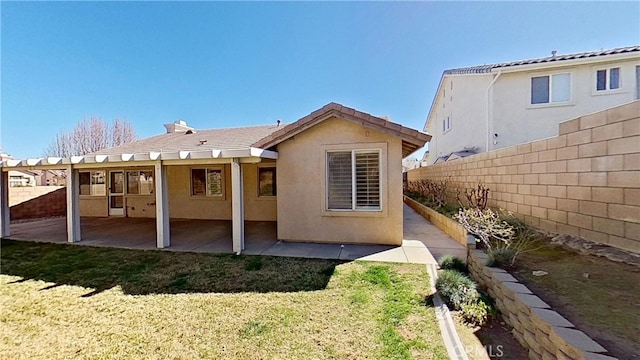 back of house with a yard, stucco siding, a patio, and fence