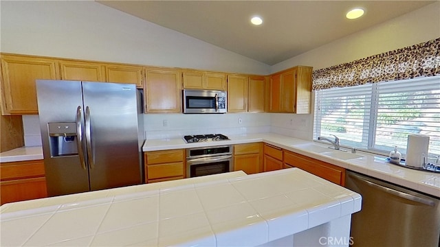 kitchen featuring recessed lighting, a sink, stainless steel appliances, tile counters, and vaulted ceiling