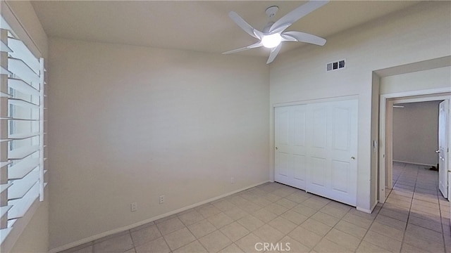 unfurnished bedroom with light tile patterned floors, baseboards, visible vents, ceiling fan, and a closet