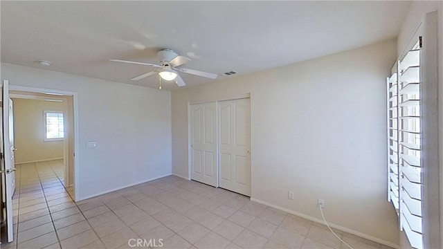 unfurnished bedroom featuring visible vents, a closet, light tile patterned flooring, baseboards, and ceiling fan