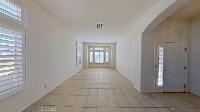 entrance foyer with light tile patterned floors, visible vents, arched walkways, and baseboards