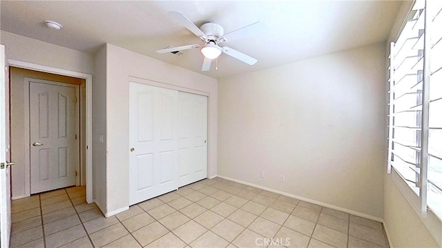 unfurnished bedroom featuring a closet, a ceiling fan, baseboards, and light tile patterned flooring