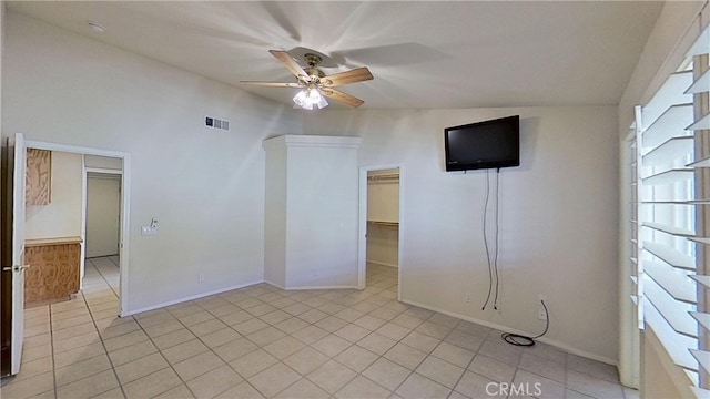 empty room featuring light tile patterned floors, a ceiling fan, visible vents, and baseboards