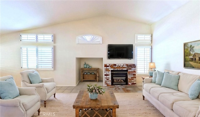 living room with vaulted ceiling, a brick fireplace, and baseboards