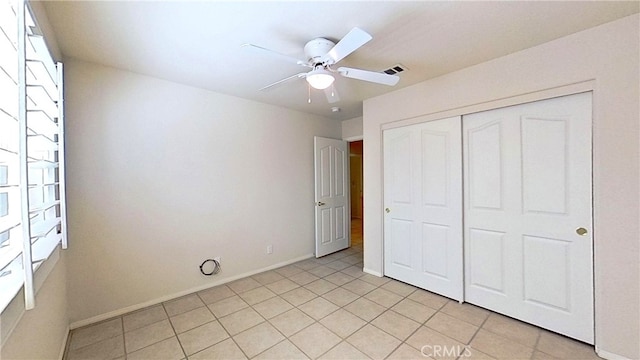 unfurnished bedroom featuring light tile patterned flooring, baseboards, visible vents, and a closet