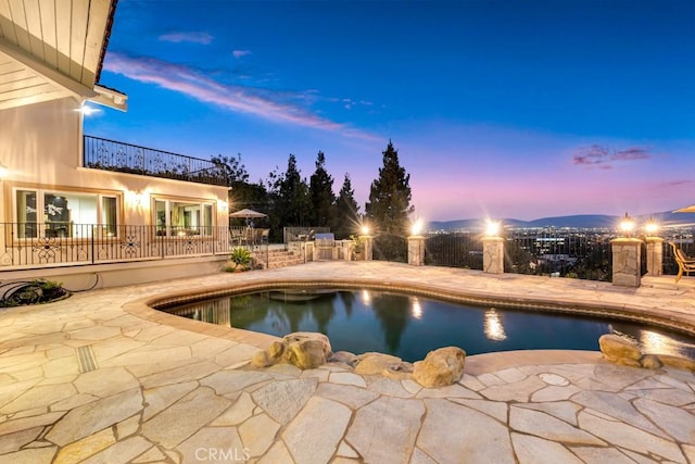 pool at dusk featuring an outdoor pool, a patio, and fence