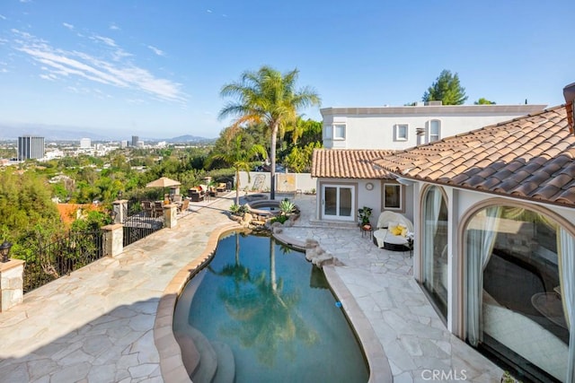 outdoor pool with a patio area, an in ground hot tub, and fence