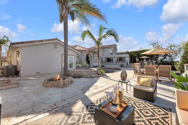 rear view of property featuring a fire pit, central AC, stucco siding, an outdoor pool, and a patio