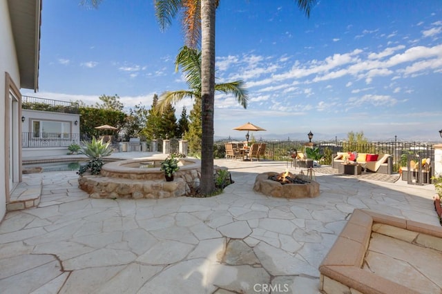 view of patio / terrace with a fenced in pool, a fire pit, and an in ground hot tub