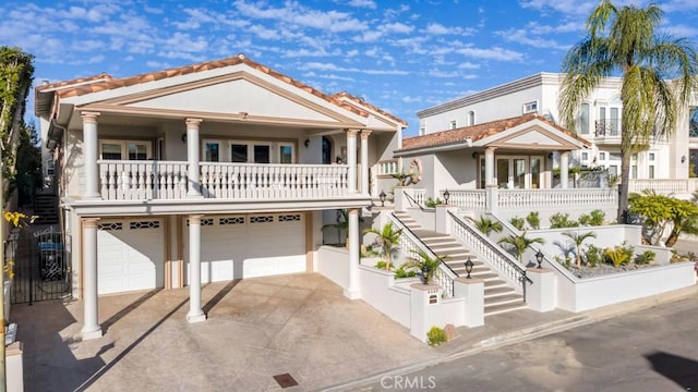 view of front of house featuring stucco siding, driveway, stairway, an attached garage, and a balcony