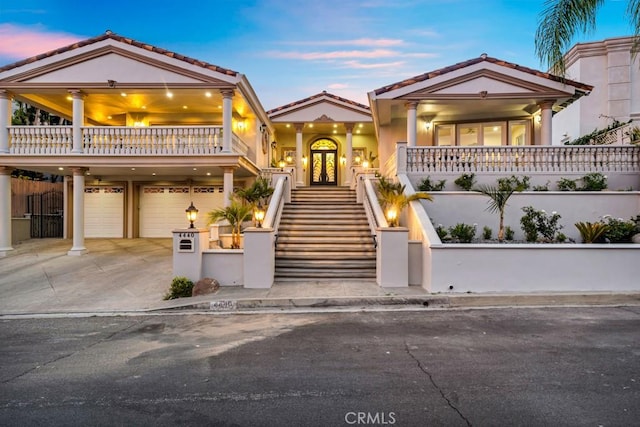 view of front of property with a tiled roof, french doors, driveway, and stairway