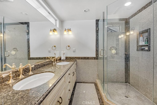 full bathroom featuring tile walls, a stall shower, wainscoting, and a sink