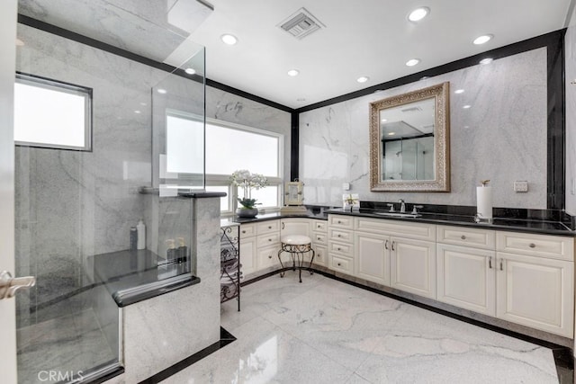 bathroom with a shower with shower door, plenty of natural light, visible vents, and marble finish floor