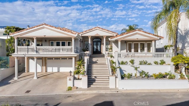 view of front of home with a porch, concrete driveway, stairs, french doors, and a garage