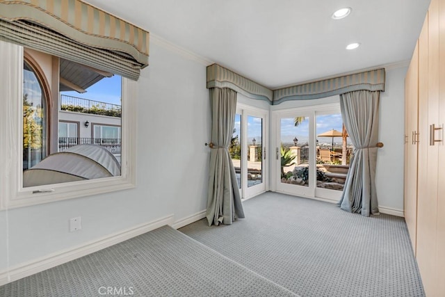 carpeted spare room featuring a wealth of natural light, crown molding, and baseboards