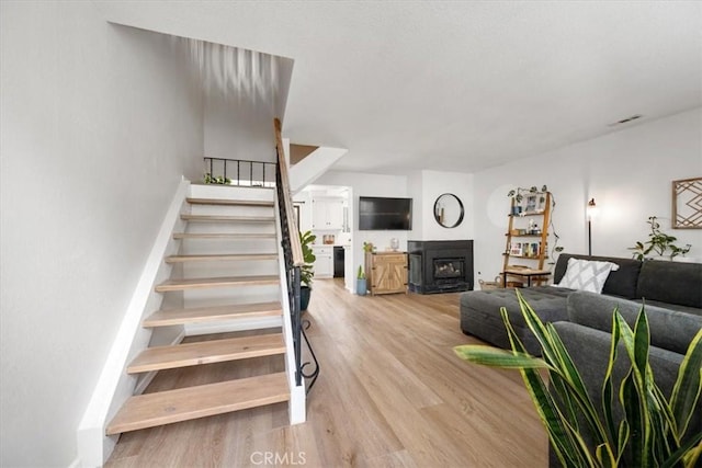 staircase featuring visible vents, a fireplace, and wood finished floors