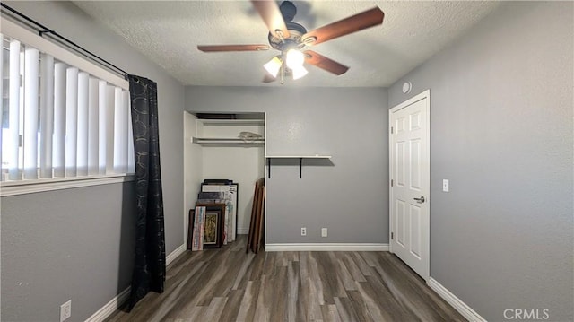 unfurnished bedroom with a textured ceiling, baseboards, and wood finished floors