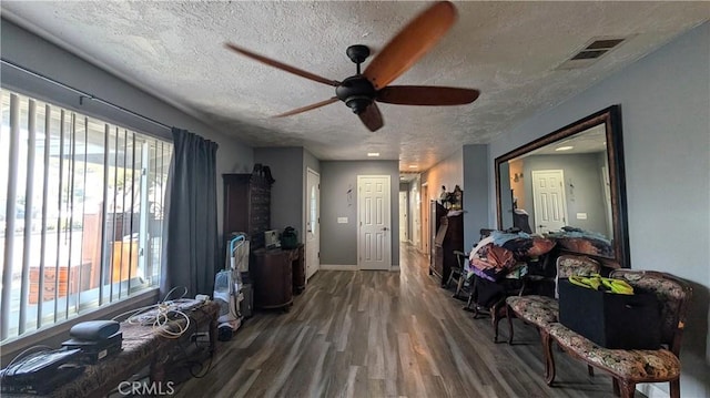 entryway with visible vents, a textured ceiling, wood finished floors, baseboards, and ceiling fan