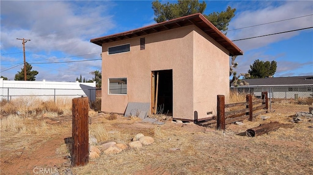 back of house featuring stucco siding and fence