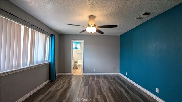 unfurnished room with a ceiling fan, wood finished floors, visible vents, baseboards, and a textured ceiling