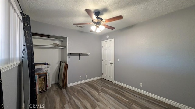 unfurnished bedroom with a textured ceiling, wood finished floors, visible vents, and baseboards