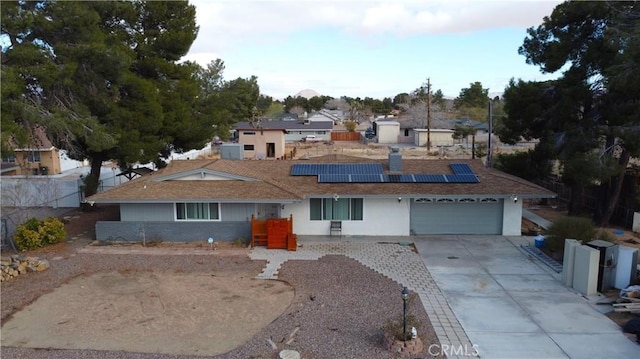 ranch-style home with roof mounted solar panels, driveway, and fence