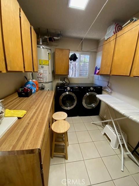 laundry area featuring gas water heater, independent washer and dryer, and light tile patterned flooring