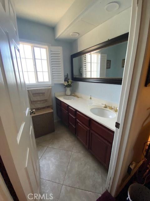 bathroom with a sink, double vanity, and tile patterned floors