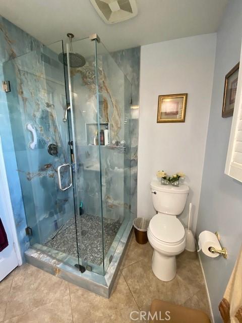 full bath featuring tile patterned flooring, a stall shower, and toilet