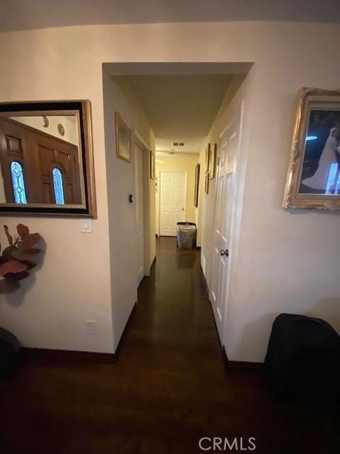 corridor with dark wood finished floors and baseboards