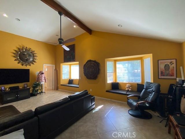 tiled living room with lofted ceiling with beams and a ceiling fan