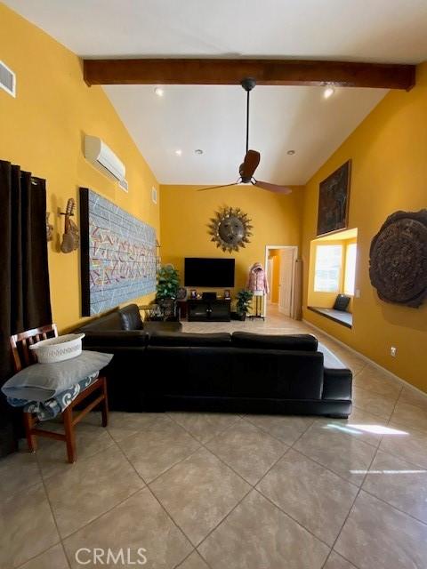 living area featuring an AC wall unit, ceiling fan, vaulted ceiling with beams, and tile patterned flooring