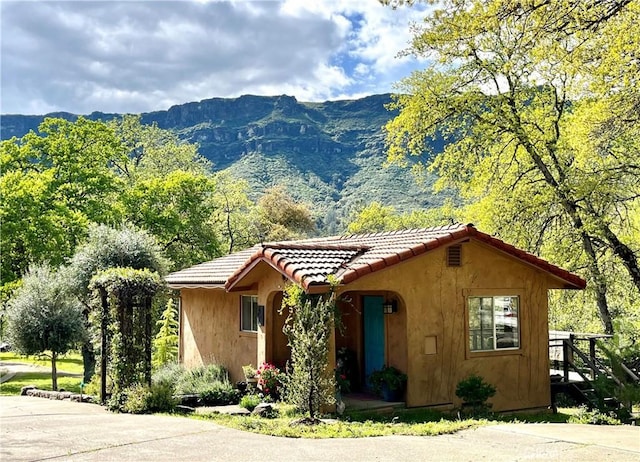 view of front of home featuring a mountain view, stucco siding, and a tiled roof