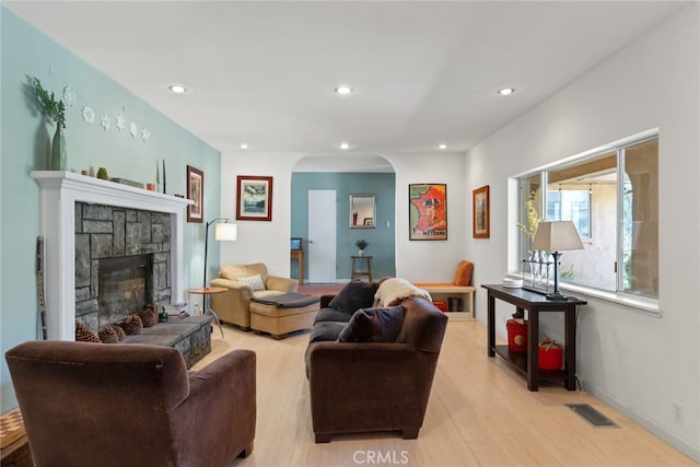 living area with visible vents, recessed lighting, arched walkways, a fireplace, and light wood finished floors