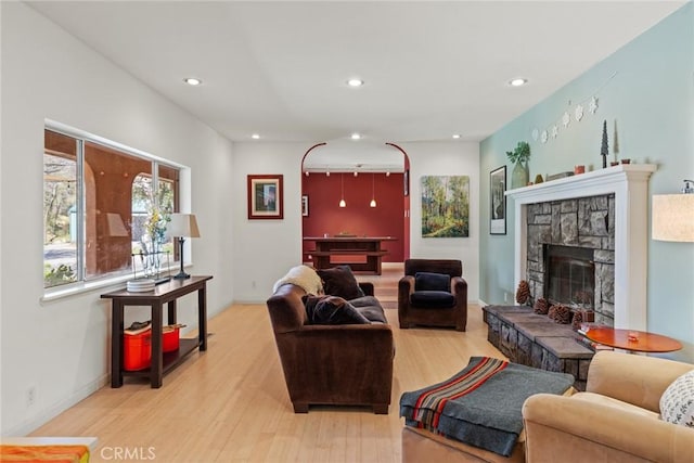 living area featuring a stone fireplace, recessed lighting, baseboards, and light wood-style floors