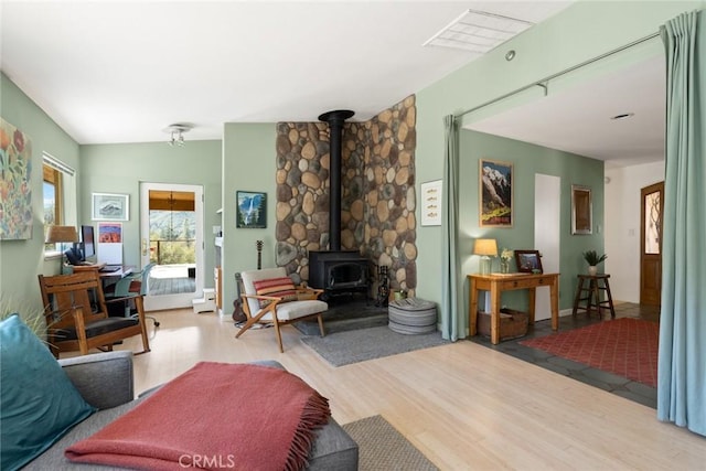 living area featuring visible vents, lofted ceiling, wood finished floors, and a wood stove