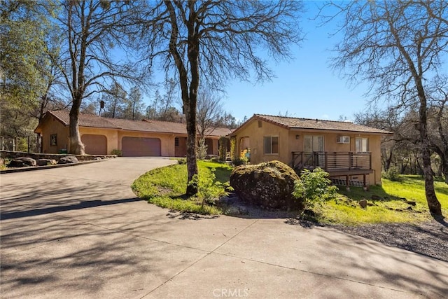 ranch-style home with stucco siding, an attached garage, and concrete driveway