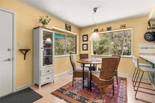 dining space with baseboards and light wood-style floors