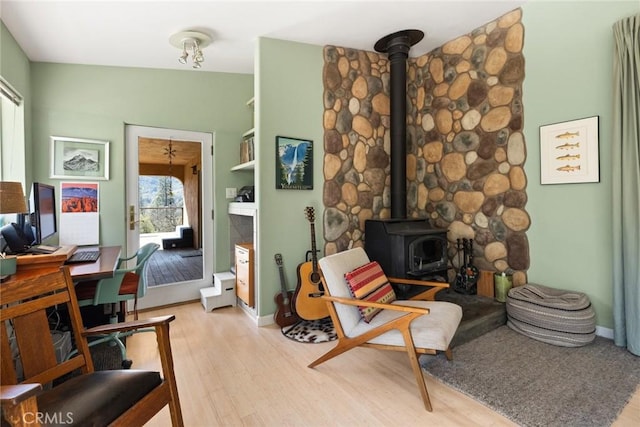 office area featuring a wood stove, baseboards, and light wood-type flooring