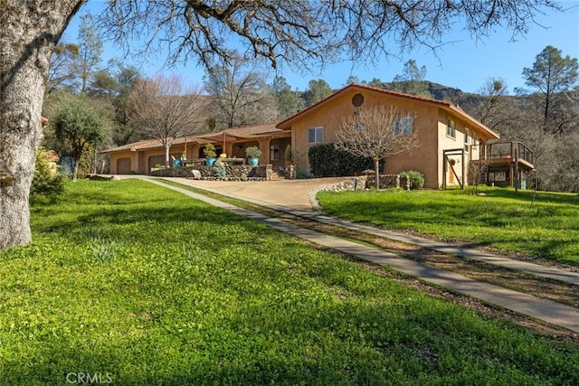 back of property with a lawn, an attached garage, and stucco siding