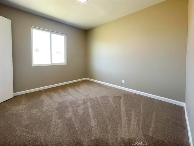 empty room featuring baseboards and carpet floors