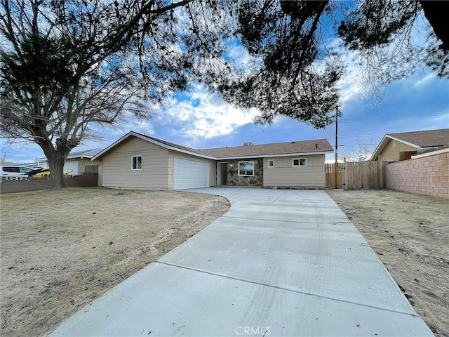 view of front of house with stone siding, concrete driveway, a garage, and fence