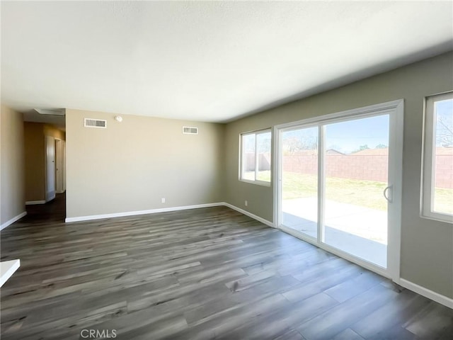 unfurnished living room with visible vents, dark wood-type flooring, and baseboards
