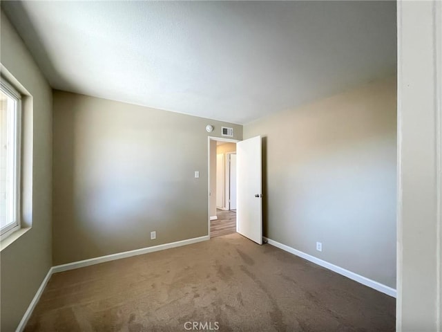 empty room with baseboards, carpet floors, and visible vents