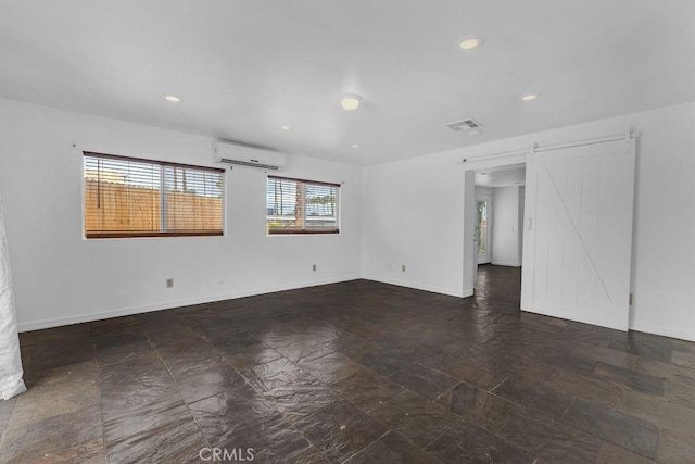 empty room with baseboards, visible vents, an AC wall unit, and a barn door