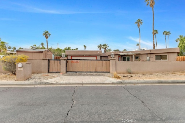 view of front of property featuring a gate, driveway, an attached garage, stucco siding, and a fenced front yard