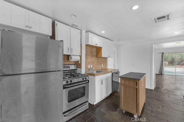 kitchen with visible vents, backsplash, appliances with stainless steel finishes, white cabinetry, and a sink