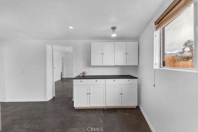 kitchen featuring recessed lighting, baseboards, dark countertops, and white cabinetry