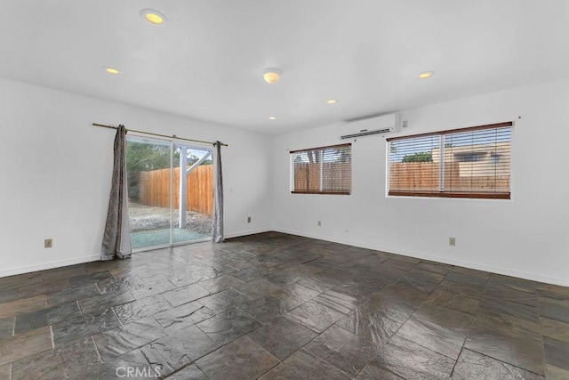 empty room with recessed lighting, baseboards, stone finish floor, and a wall mounted AC